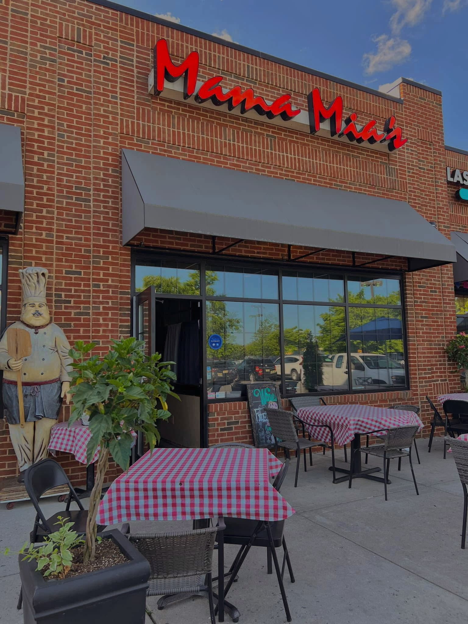 Charming exterior of Mama Mia's with outdoor seating and red checkered tablecloths